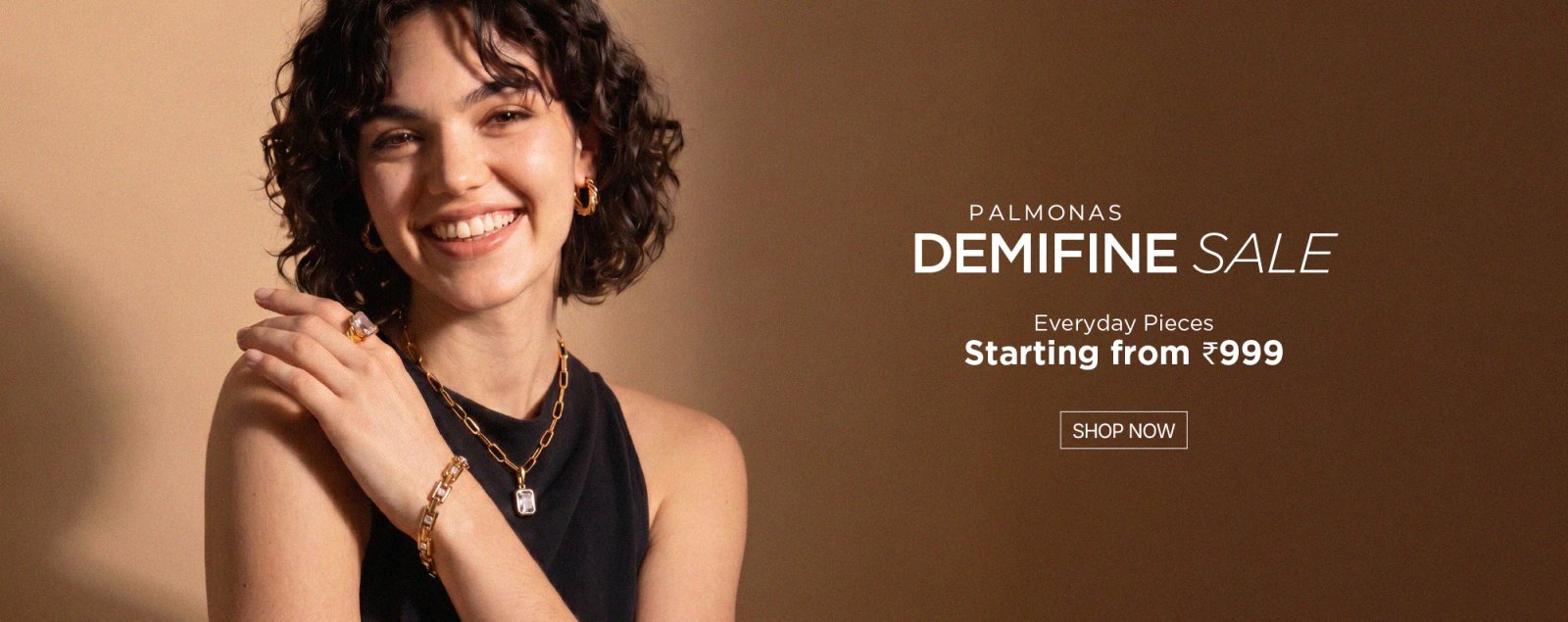 Smiling model in a black dress wearing layered gold chains, announcing the Palmonas Demifine Sale with pieces from ₹999